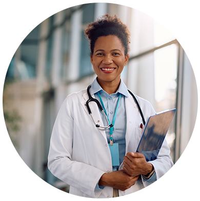 Médica sorridente com jaleco e estetoscópio pronta para atendimento em ambiente hospitalar.