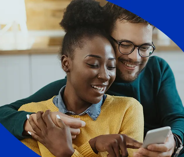 Casal sorrindo olhando celular juntos em momento descontraído