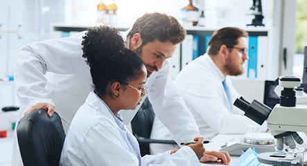 Pesquisadores analisando dados em laboratório com microscópios e computadores.