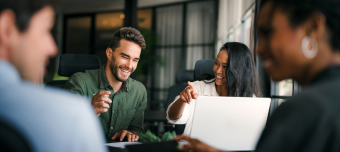 Equipe sorrindo em reunião com laptop no escritório.