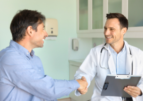 Médico em consultório cumprimenta paciente durante atendimento em unidade de oncologia, simbolizando cuidado humanizado e confiança.