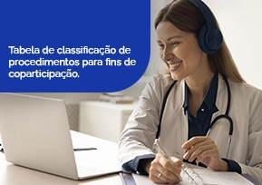Medica sorrindo, com a caneta na mão e olhando para o notebook.