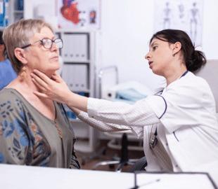Médica examinando a tireoide de uma paciente idosa, simbolizando o Dia Internacional da Tireoide e a importância da saúde da tireoide.