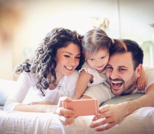 Família (pai, mãe e filha) sorrindo e tirando uma selfie, simbolizando a disponibilidade de mais especialidades médicas no Centro Clínico Joinville.