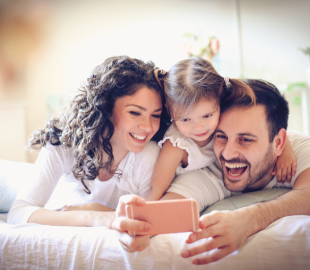 Família (pai, mãe e filha) sorrindo e tirando uma selfie, simbolizando a disponibilidade de mais especialidades médicas no Centro Clínico Joinville.