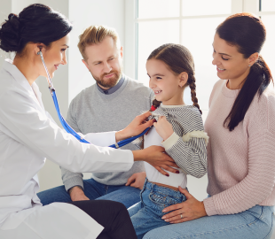 Médica sorridente examinando uma menina com um estetoscópio, enquanto os pais observam com carinho, simbolizando o atendimento pediátrico no Centro Clínico Pinheirinho e a alteração de horário.