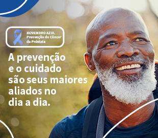 Homem idoso negro, sorrindo e de barba branca, com um banner ao lado que diz Novembro Azul Prevenção do Câncer de Próstata e a frase A prevenção e o cuidado são seus maiores aliados no dia a dia, simbolizando a importância do diagnóstico precoce.