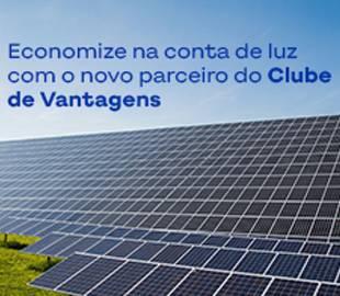 Painéis solares fotovoltaicos, com o texto Economize na conta de luz com o novo parceiro do Clube de Vantagens sobreposto no céu azul.