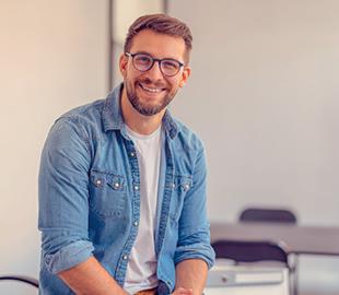 Homem de óculos e camisa jeans, sorrindo e olhando para a câmera, simbolizando o comunicado sobre o novo endereço do Centro Clínico Indaial.
