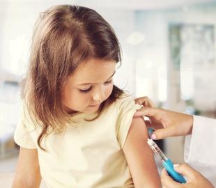 Criança recebendo vacina no braço em consultório médico, simbolizando a importância da imunização infantil para prevenção de doenças
