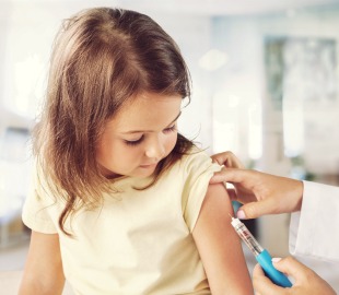Criança recebendo vacina no braço em consultório médico, simbolizando a importância da imunização infantil para prevenção de doenças