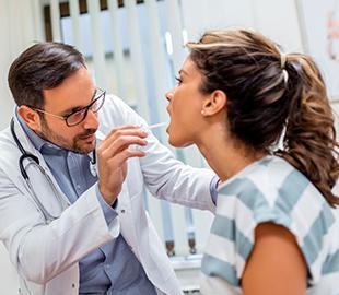Médico examinando o coração de um menino pequeno com um estetoscópio, enquanto os pais sorriem ao lado, simbolizando os benefícios de um plano de saúde familiar.