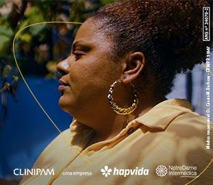 Mulher de perfil com cabelo curto e encaracolado, usando uma camisa amarela e brincos de argola, em um ambiente externo, simbolizando o Dia Internacional da Mulher.