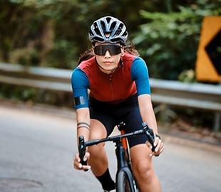 Ciclista com capacete e óculos em uma bicicleta de estrada, simbolizando esportes recomendados para fisioterapia.