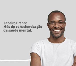 Homem negro sorridente, usando óculos, com a frase Janeiro Branco: Mês de conscientização da saúde mental. ao lado, simbolizando a campanha e a importância da saúde mental.