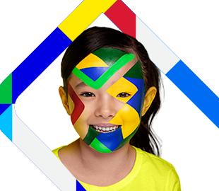 Criança sorridente com o rosto pintado com formas geométricas nas cores da bandeira do Brasil, simbolizando a campanha Julho Neon e a saúde bucal.