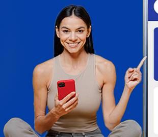 Mulher sorridente sentada, segurando um celular vermelho e apontando para um elemento visual à direita, simbolizando a mudança do aplicativo Clinipam para Hapvida Clinipam.