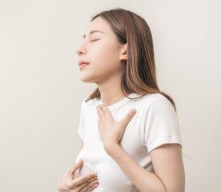 Mulher com expressão de desconforto, segurando o peito, simbolizando azia ou dor torácica associada à doença do refluxo gastroesofágico