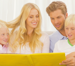 Família feliz (pai, mãe e dois filhos) lendo um livro juntos, simbolizando o cuidado familiar e a disponibilidade de mais especialidades médicas em Florianópolis.