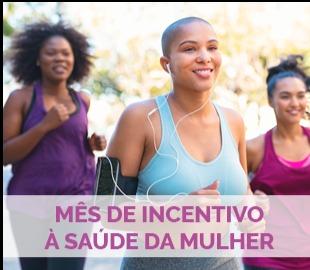 Três mulheres sorrindo e correndo juntas ao ar livre, com a frase MÊS DE INCENTIVO À SAÚDE DA MULHER sobreposta, simbolizando a saúde, bem-estar e o cuidado feminino.
