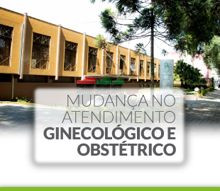 Fachada de um hospital ou clínica, com a frase MUDANÇA NO ATENDIMENTO GINECOLÓGICO E OBSTÉTRICO sobreposta, simbolizando a alteração de local de atendimento.