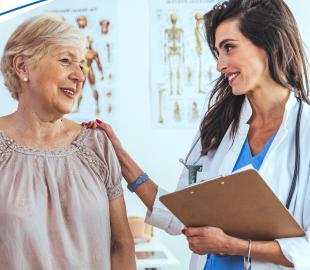 Médica sorridente de jaleco branco, segurando uma prancheta, com a mão no ombro de uma paciente idosa, ambas sorrindo, simbolizando a mudança na rede de atendimento em Curitiba.