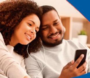 Casal feliz, usando o mesmo fone de ouvido, olhando para um smartphone, simbolizando a comunicação e o acompanhamento de informações sobre o reajuste anual de planos de saúde individuais.