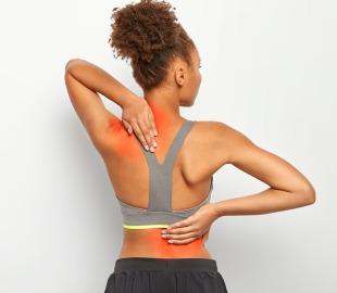 Mulher de costas, tocando a nuca e a região lombar, com áreas vermelhas destacadas indicando dor, simbolizando os sintomas da fibromialgia.