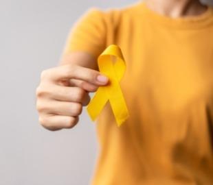 Mão segurando uma fita amarela de conscientização, simbolizando a campanha Setembro Amarelo e a prevenção do suicídio através do tratamento da depressão.