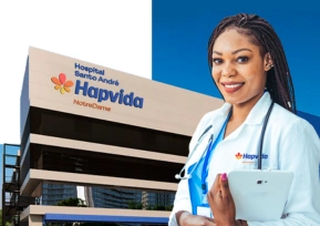 Médica sorridente em frente ao Hospital Santo André da Hapvida NotreDame, representando a expansão da rede própria.